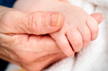 A Grandmother holding hands with a baby